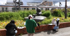 電車や彫刻など駅前を写生中